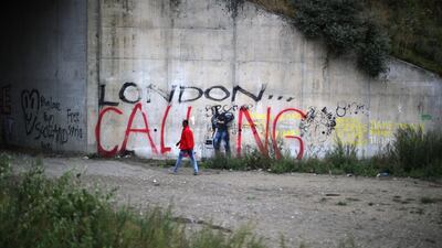 A migrant at the Jungle camp, walks past graffiti on September 5, 2016. Getty Images