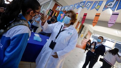 A doctor checks the body temperature of a child arriving at the Ignacio Zaragoza elementary school as Mexico City's authorities resumed in-person classes. Reuters