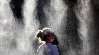 A woman cools off under a mist sprayer during a heatwave in Bordeaux. AFP