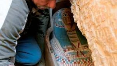 An Egyptian worker brushes the dust off a wooden coffin containing a linen-wrapped mummy found in a necropolis south-east of the pyramid field of Lahun at the entrance of Egyptís Fayyum oasis, some 130 km southwest of Cairo.