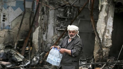 A man carries water bottles in an area of Idlib damaged by shelling from forces loyal to Bashar Al Assad after rebels took control of the city. Mahmoud Hebbo / Reuters / March 29, 2015