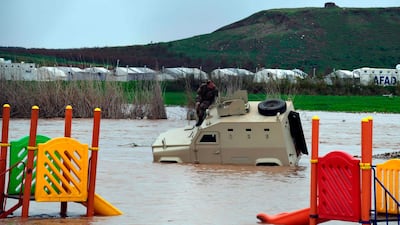 A Turkish-backed Syrian rebel stand atop a submerged vehicle in a flooded area near Deir Al Ballut refugee camp in Afrin's countryside, along Syria's northern border with Turkey on March 31, 2019. AFP