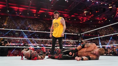 Dominik Mysterio stands over his father Rey Mysterio, and Edge, after betraying them.