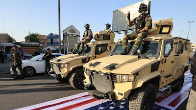 Paramilitary vehicles drive over the American flag during a procession in Baghdad. AFP