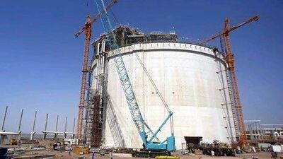 Workers walk past a LNG tank at the site of a giant gas exporting project in the Arabian Sea. REUTERS/Khaled Abdullah