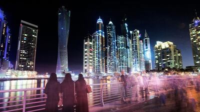 Groups of people come and go to admire the colourful skyline of the Dubai marina at night. Jaime Puebla / The National