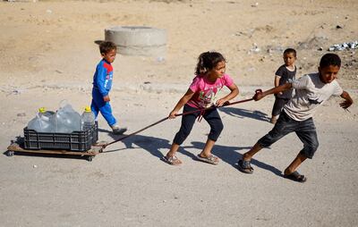 Palestinian children pull water containers as people flee Rafah after Israeli forces launched a ground and air operation in the eastern part of the city. Reuters