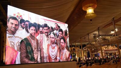 Indian mining tycoon, Gali Janardhan Reddy, centre, is seen on a big screen as he poses with his daughter Bramhani during her lavish wedding AFP PHOTO / STRINGER