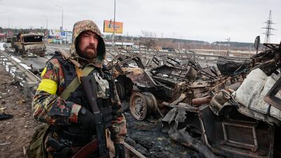 An armed man stands by the remains of a Russian military vehicle in Bucha. AP