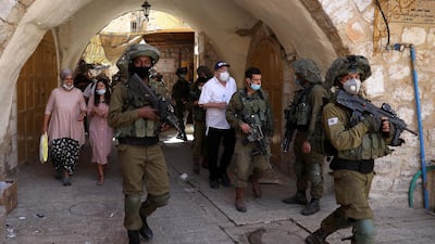 Israeli soldiers and a group of Jewish settlers in protective masks during a weekly guided tour in the old city of Hebron, amid the ongoing coronavirus Covid-19 pandemic in the West Bank. EPA