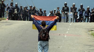 A Venezuelan opposition activist waves a flag in front of a police line during a demonstration in San Cristobal. George Castellanos / AFP Photo