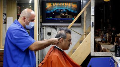 An Iranian hairdresser works as the first presidential candidates' TV debate shows presidential candidate Ebrahim Raisi speaking. EPA