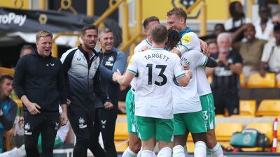 Newcastle United manager Eddie Howe, left, watches as Allan Saint-Maximin celebrates with teammates after scoring the late leveller against Wolves on Saturday, August 28, 2022. Getty