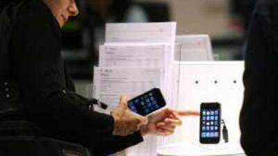 A customer examines a new Apple iPhone at the T-Mobile store in Budapest, Hungary: makers of high-end software and computer products are already feeling a positive shift in consumer sentiment.