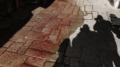 The shadows of photographers taking photos of blood stains on November 29, 2015, at Damascus Gate, a main entrance to Jerusalem’s Old City, where a Palestinian man stabbed and seriously wounded an Israeli border policeman before being killed by Israeli officers. The attack brought to 99 the number of Palestinians killed in a wave of unrest since October 1. Over half of them have been alleged perpetrators of stabbing, shooting and car-ramming attacks aimed at Israeli civilians and security forces. Ahmad Gharabli / Agence France-Presse