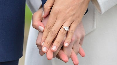 Meghan Markle wears her engagement ring as she poses with Britain's Prince Harry in the grounds of Kensington Palace in London. Dominic Lipinski / PA via AP