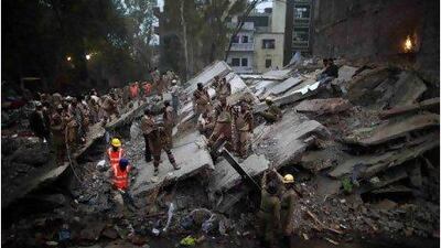 Rescue workers yesterday search for bodies amid debris after a four-storey apartment building collapsed in New Delhi.