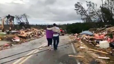 People walk amid debris in Lee County, Alabama. AP Photo