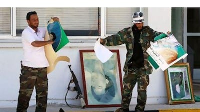 Rebel fighters destroy posters of Libyan leader Muammar Qaddafi which were found in the administrative center after rebels seized control of the Zawiyah oil refinery Thursday.