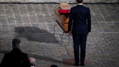 French President Emmanuel Macron pays his respects by the coffin of slain teacher Samuel Paty in the courtyard of the Sorbonne university during a national memorial event, in Paris, France October 21, 2020. REUTERS