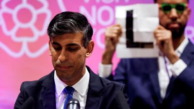 Independent candidate Niko Omilana holds an 'L' sign behind Rishi Sunak as he speaks after winning his seat at Richmond and Northallerton. The Conservative Party lost the general election. Reuters