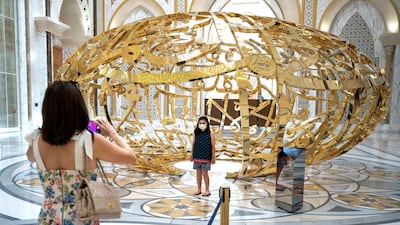 Visitors take a photograph in front of an artwork by Mattar Bin Lahej.