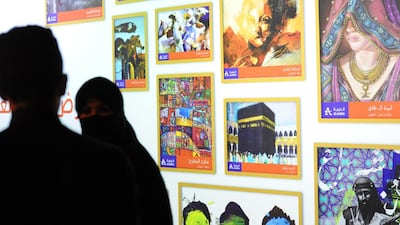 Saudi artists stand in front of paintings displayed during a showcase of Saudi art on streetside billboards on December 22, 2014, on Tahlia street in Riyadh. Fayez Nureldine / AFP