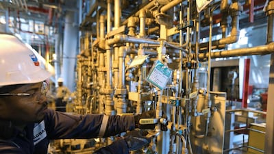 An oil worker uses a metal wrench to check pipework aboard the Agbami floating production, storage and offloading vessel. George Osodi / Bloomberg