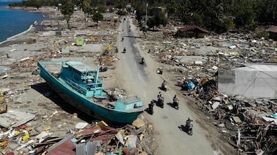 People drive past a washed up boat. AFP
