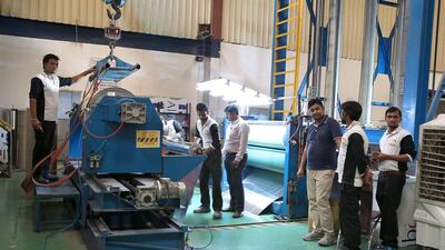 Above, workers make Alubond sheets at the Mulk Holdings facility at Hamiryah Free Zone. Pawan Singh / The National