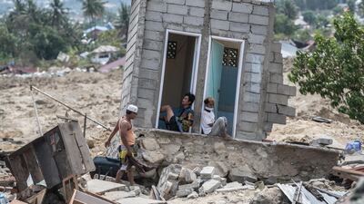People rest in what was a toilet block in an area of Palu that was completely destroyed by the earthquake and tsunami. Getty Images