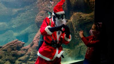 Dressed as Santa Claus, a diver makes the heart symbol to a young girl at the Creta Aquarium in the city of Heraklion on the Greek southern island of Crete, December 15. AFP
