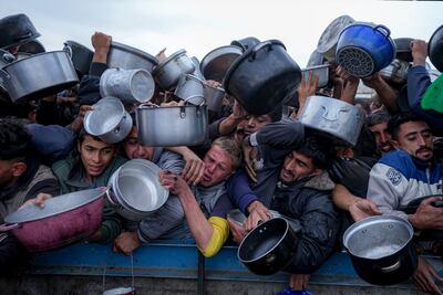 Palestinians struggle to reach for food at a distribution centre in Khan Younis, Gaza Strip. AP