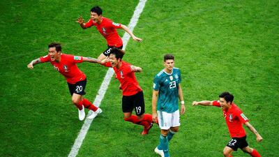 South Korean players celebrate next to Mario Gomez of Germany. South Korea's victory sent defending champions Germany out of the tournament. Diego Azubel / EPA