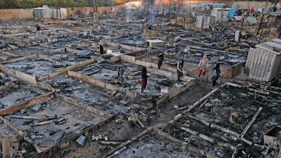 Syrian refugees walk through the wreckage of their shelters at a camp which was burnt down after a fight between residents and a local family. AFP