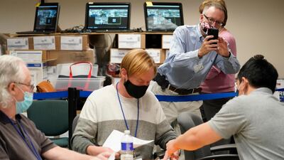 Republican canvas observer Ed White, takes photos with his smart phone as Lehigh County workers count ballots as vote counting continues in Allentown Pennsylvania. AP Photo