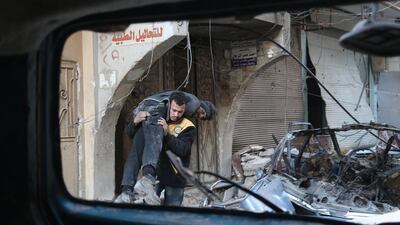 A member of the Syrian White Helmets, carries a wounded man away from the shelling in the rebel-held town of Hamouria. Abdulmonam Eassa / AFP Photo