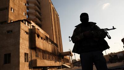 A fighter with Hayat Tahrir Al Sham stands outside the Palestine Branch security complex in Damascus, Syria. Reuters
