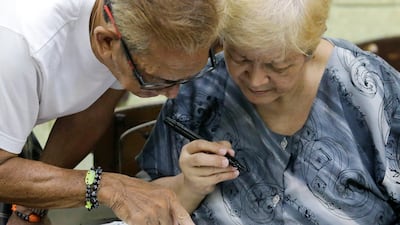 A man helps his wife fill out her ballot. AP Photo
