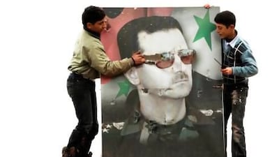 Two boys destroy a poster of Syria's president Bashar Al Assad at the Syrian Army base at Hawa village, north Aleppo, which rebels took control of yesterday.
