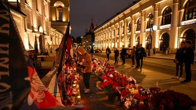 The woman lights her candle as others stand watching at the informal street memorial. AP
