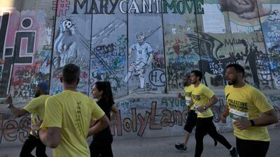 Participants run past a section of Israel's controversial barrier in Bethlehem, in the Israeli-occupied West Bank. AFP