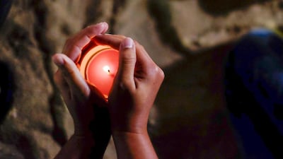 A mourner shields a candle flame for murdered American Ibolya Ryan. (Antonie Robertson / The National)