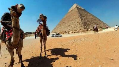 Egyptian men ride their camels as they wait for customers in front of the pyramid of Khafre in Giza, southwest of central Cairo.