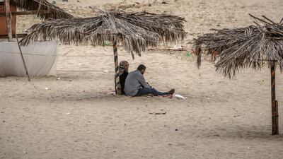 Palestinians sit on the beach of Gaza City, EPA