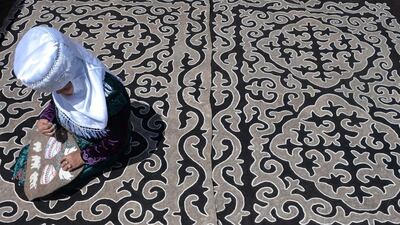 A woman wearing a traditional Kyrgyz dress sits on a felt carpet during a traditional folk festival at Son-Kul lake, 3016 metres above the sea level, some 350 kms from Bishkek on July 29, 2016. The festival marks the 220th anniversary of the national hero Tailak Baatyr. Vyacheslav Oseledko / AFP