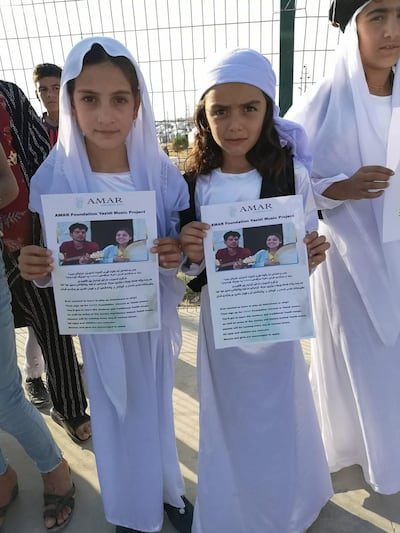 Yazidi children show posters of the Amar project.