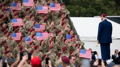 Members of the military hold US flags as Mr Trump arrives at Fort Bragg, North Carolina, in 2025. Getty Images