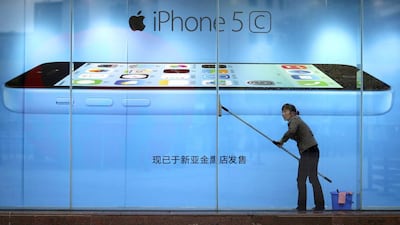 A worker cleans glass in front of an iPhone 5C advertisement at an apple store in China. Apple has launched a cheaper version of the 5C in a number of locations around the world. Wong Campion / Reuters