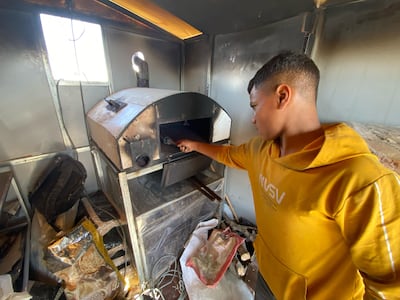 Preparing the pizza oven in the trailer. Mohammed Abu Amra for The National